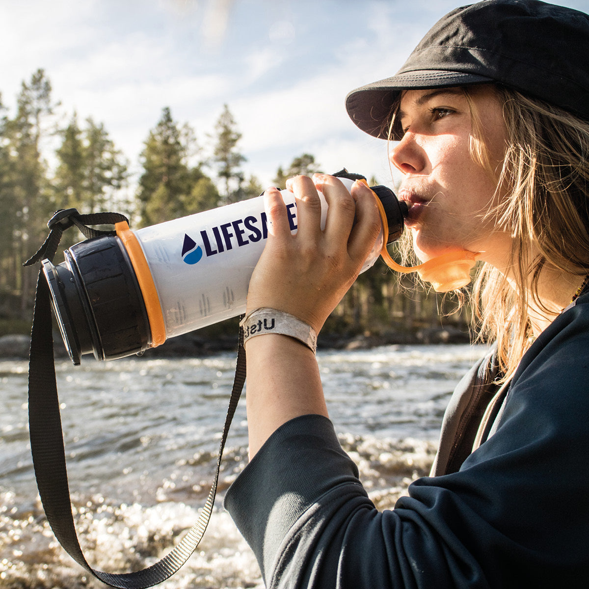 Woman drinking river water purified by a LifeSaver Bottle