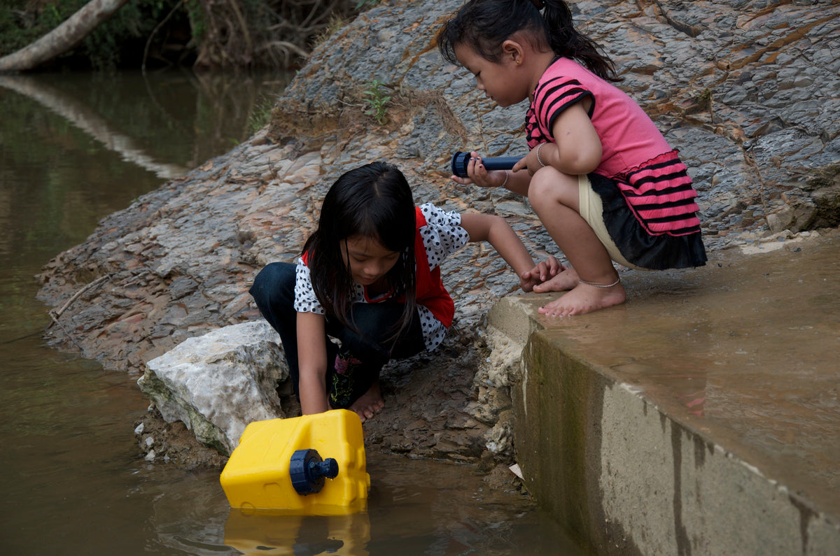 Children in the Philippines filling a yellow LifeSaver Cube from a river