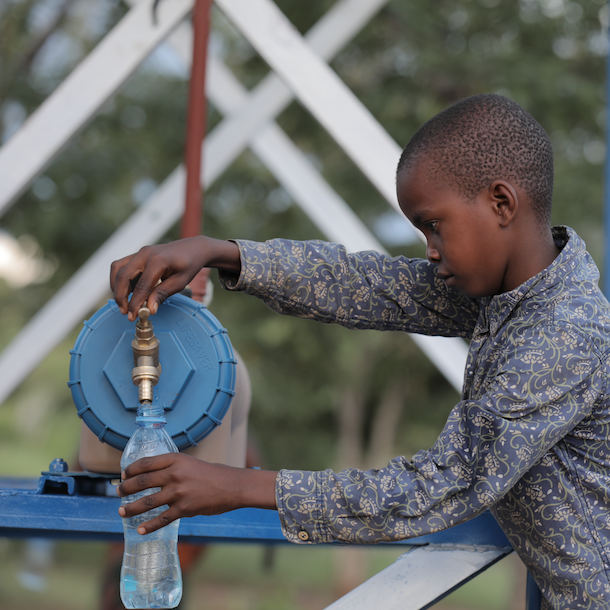 Load image into Gallery viewer, Child in Africa filling a bottle with water from a LifeSaver C1
