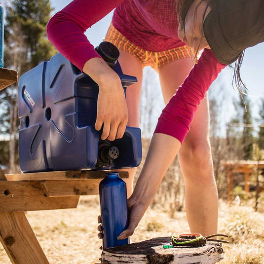 Person camping using the LifeSaver water purification Jerrycan to fill a bottle of clean water