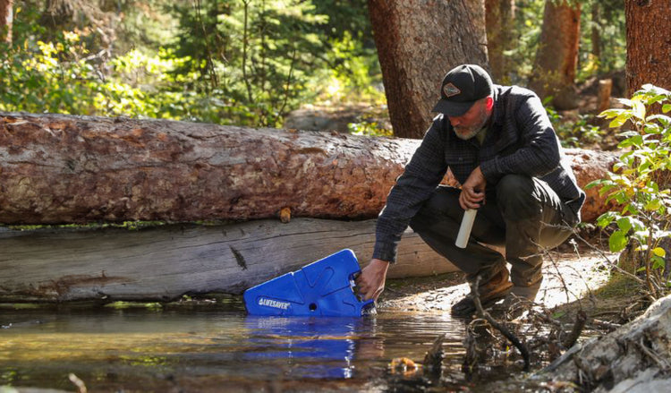 A man filling a blue LifeSaver Jerrycan from the shores a of a lake